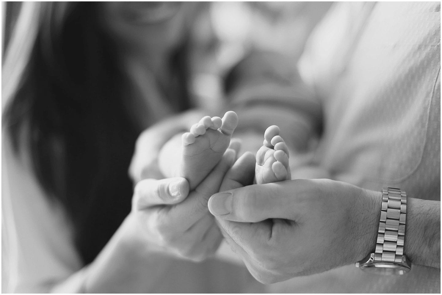 parents holding newborn baby feet