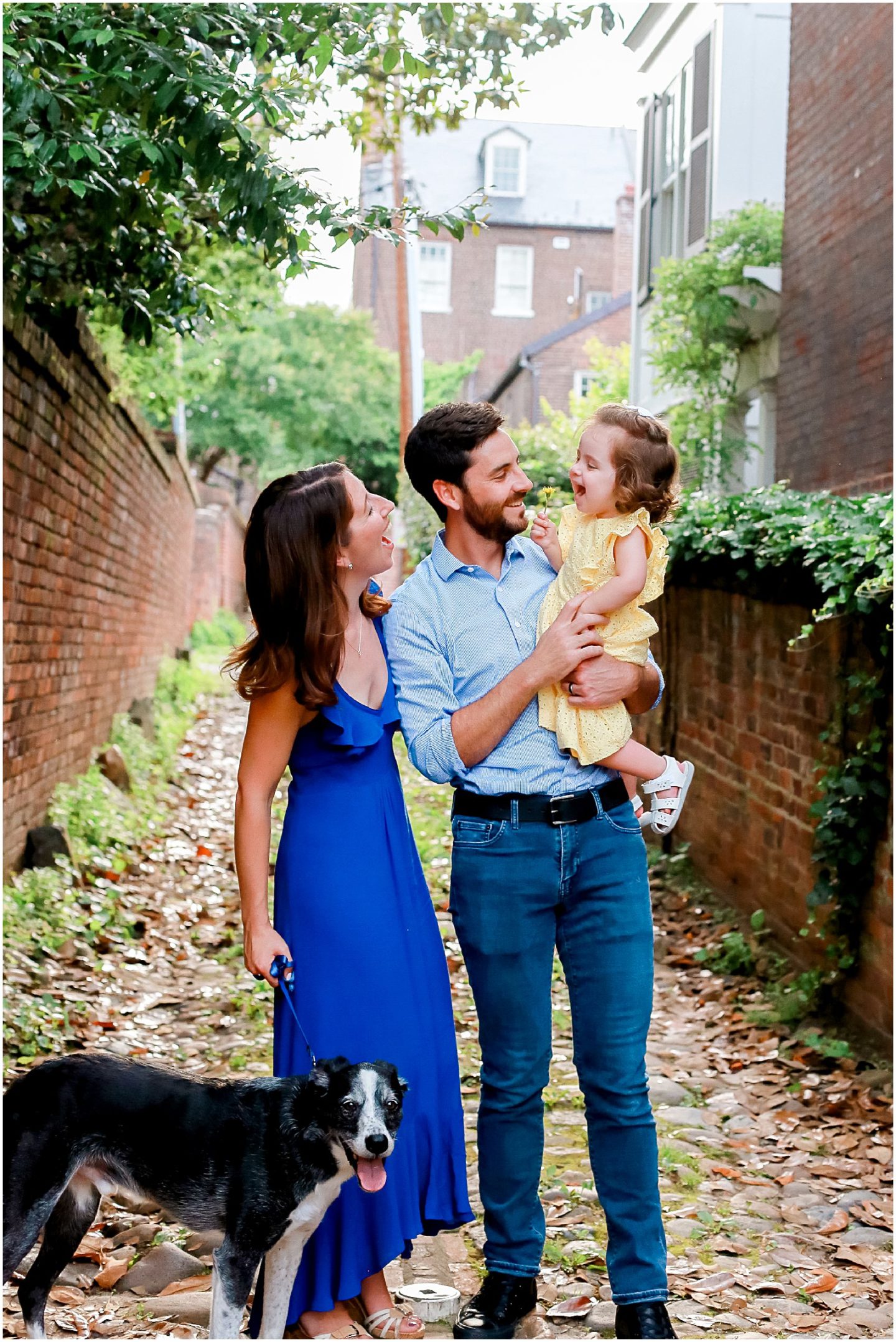 Family with dog cuddling child on Wales Alley in Old Town Alexandria