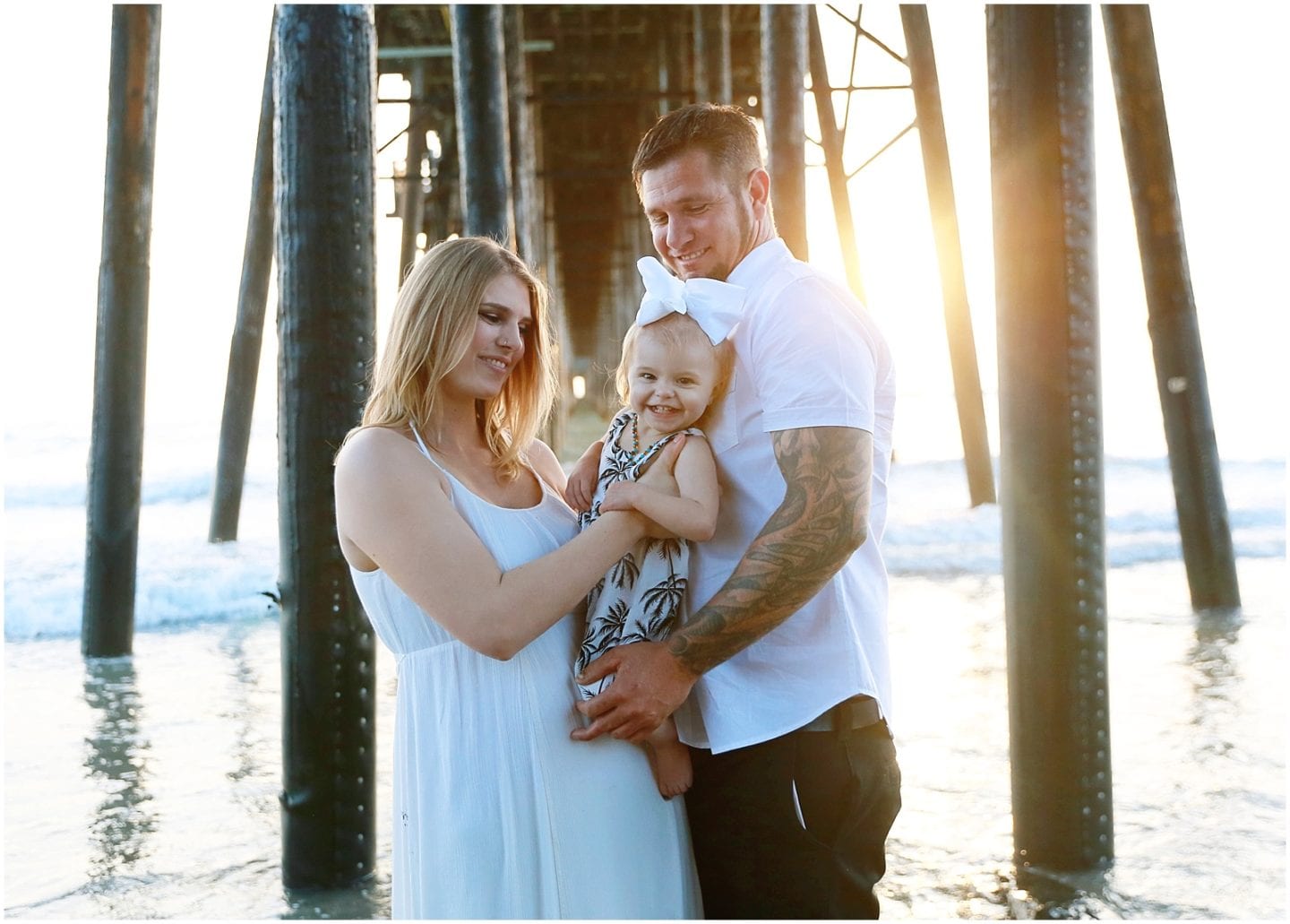 family photo session at beach laughing with baby wearing white classic outfits 