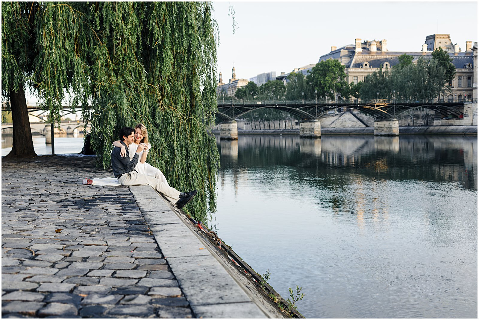 couple picnicing along the Pont Neuf willow tree in Paris