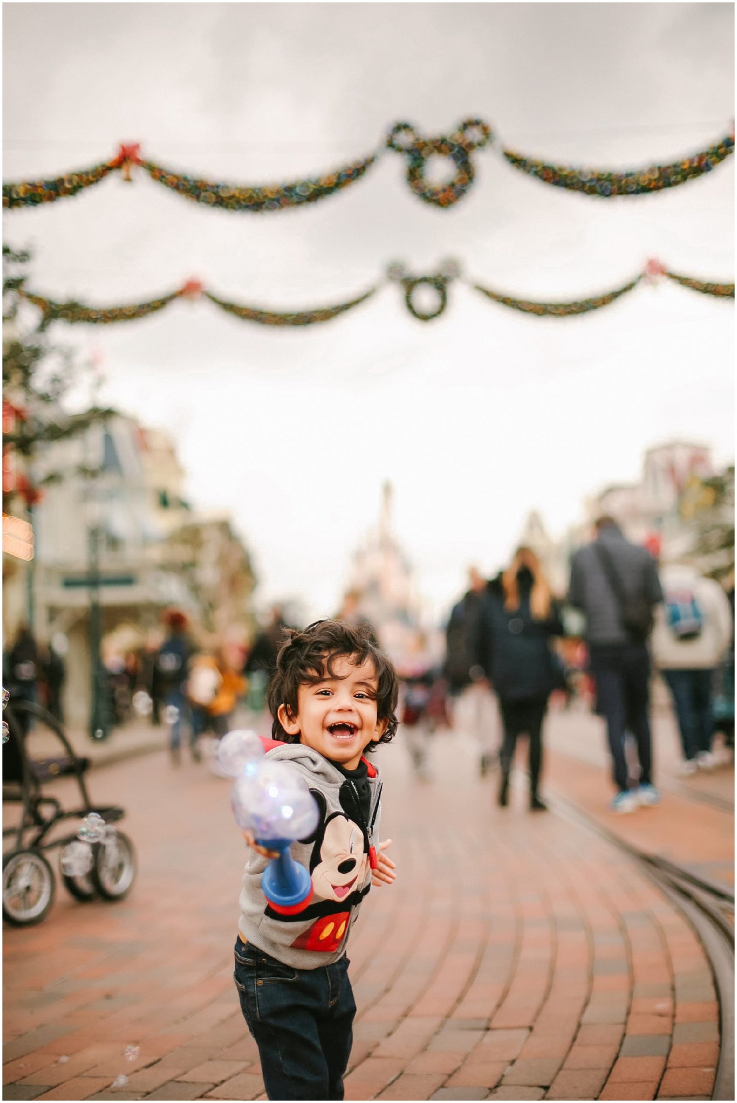 child with bubbles on Main Street Disneyland Paris with Disney vacation family photographer | Helena Woods Photography