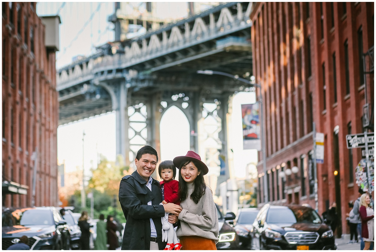 family smiling in front of Manhattan Bridge in DUMBO Brooklyn | Helena Woods nyc family photographer