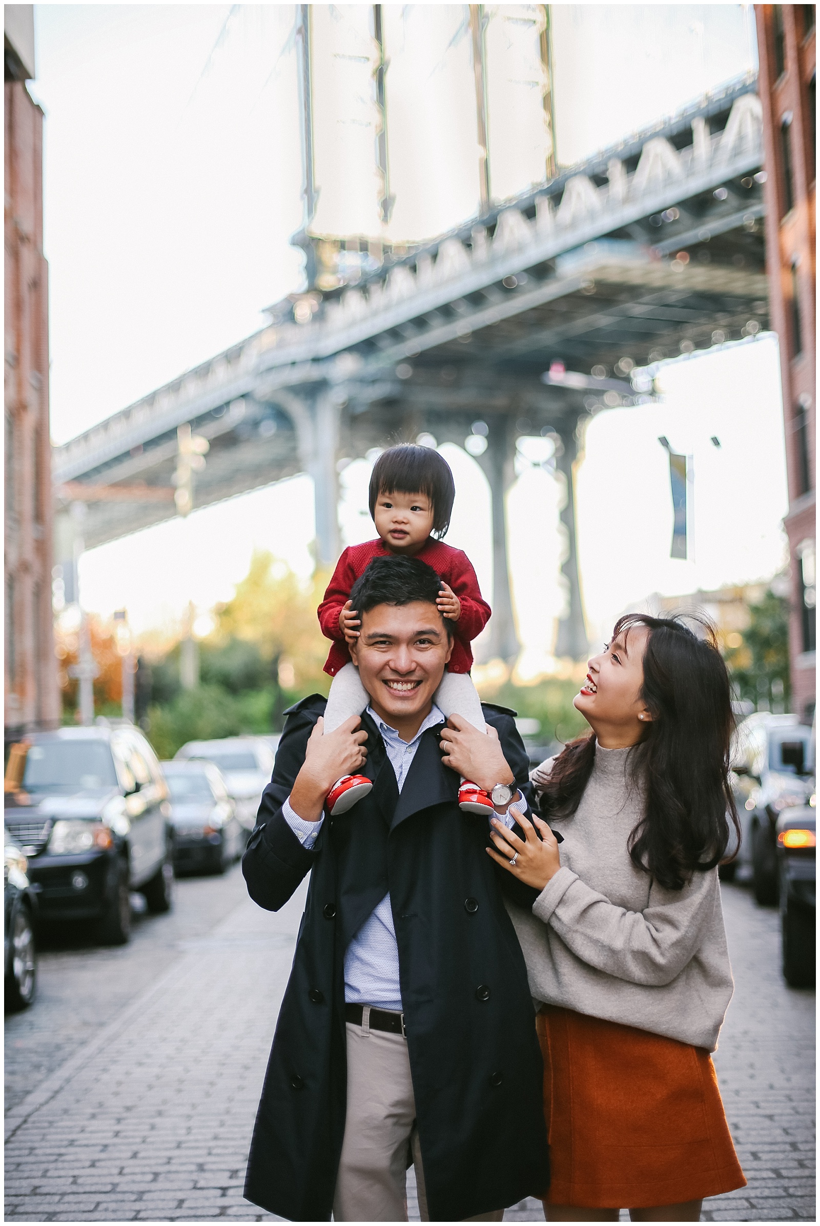 family smiling on water street overlooking Manhattan Bridge in Brooklyn NYC