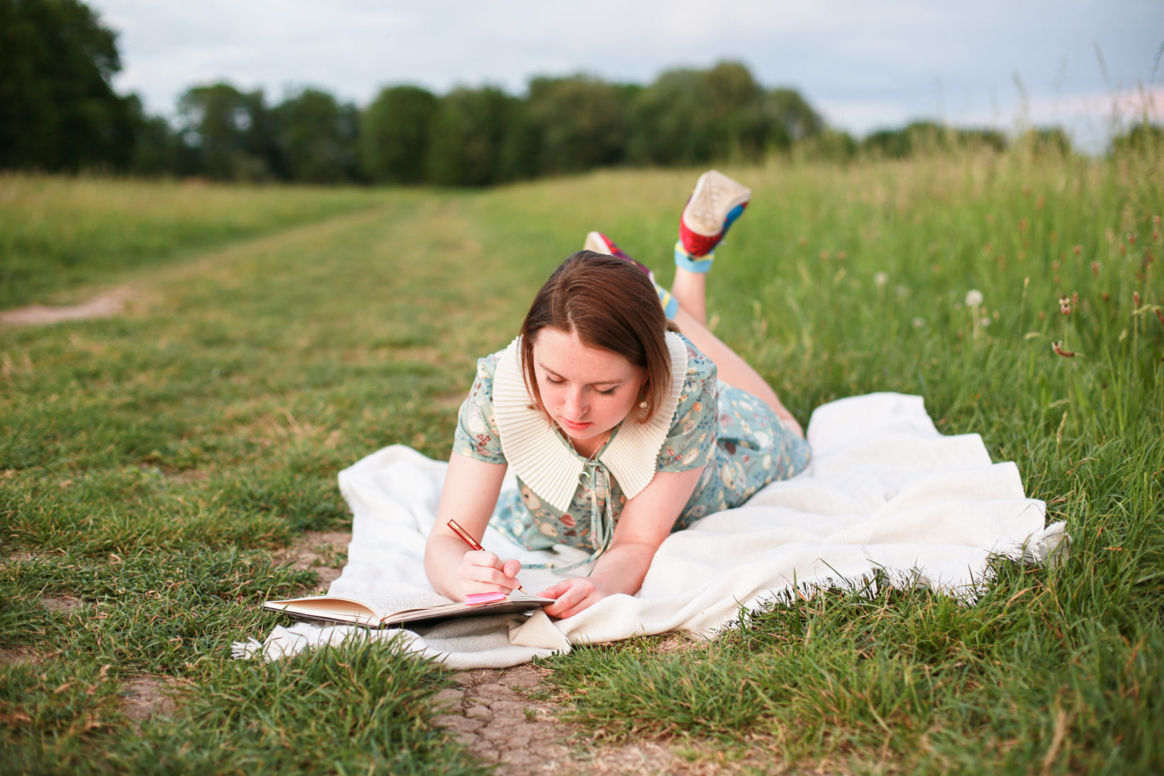 girl writing in field how to hygge in summer