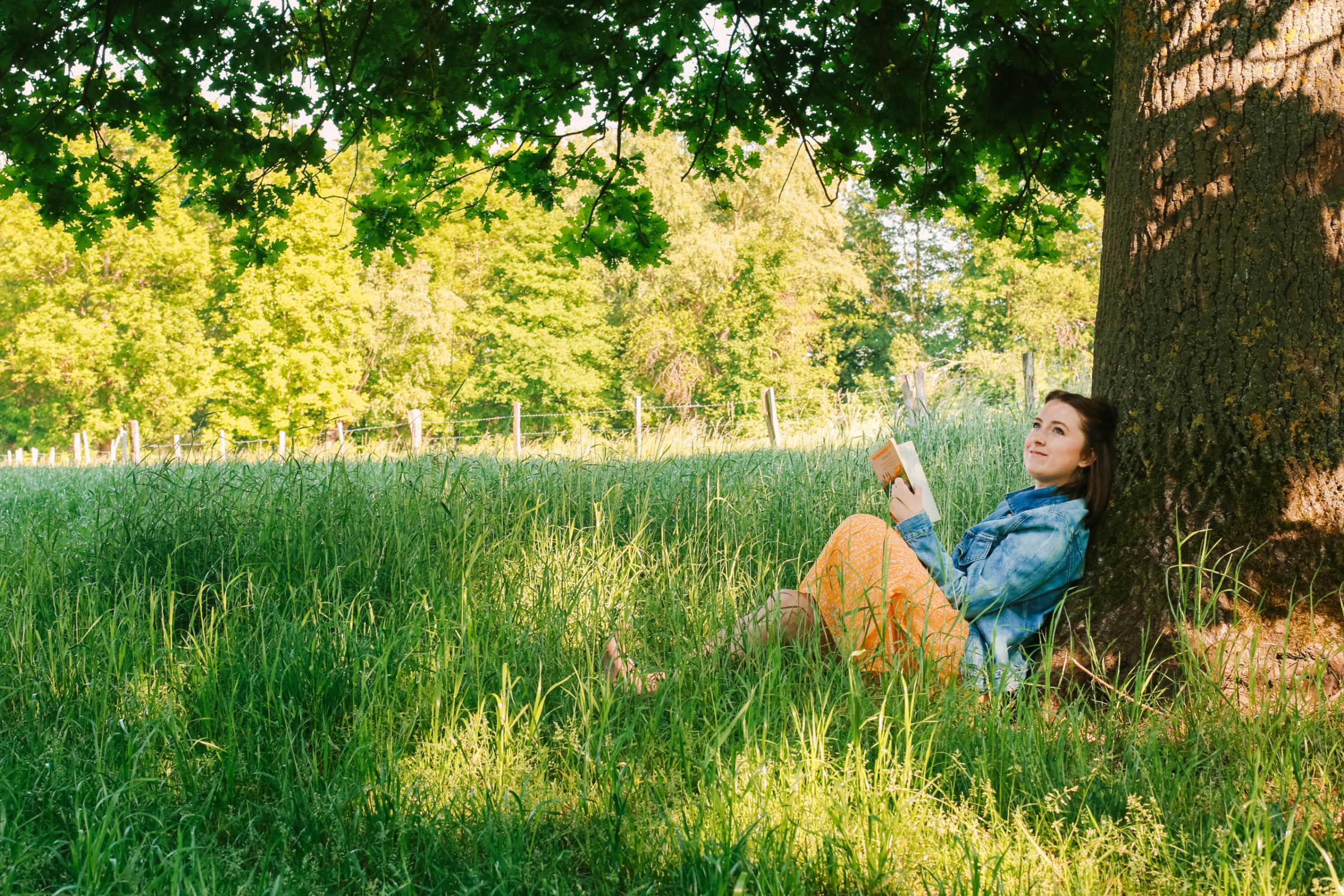 girl reading against tree sharing how to hygge in summer