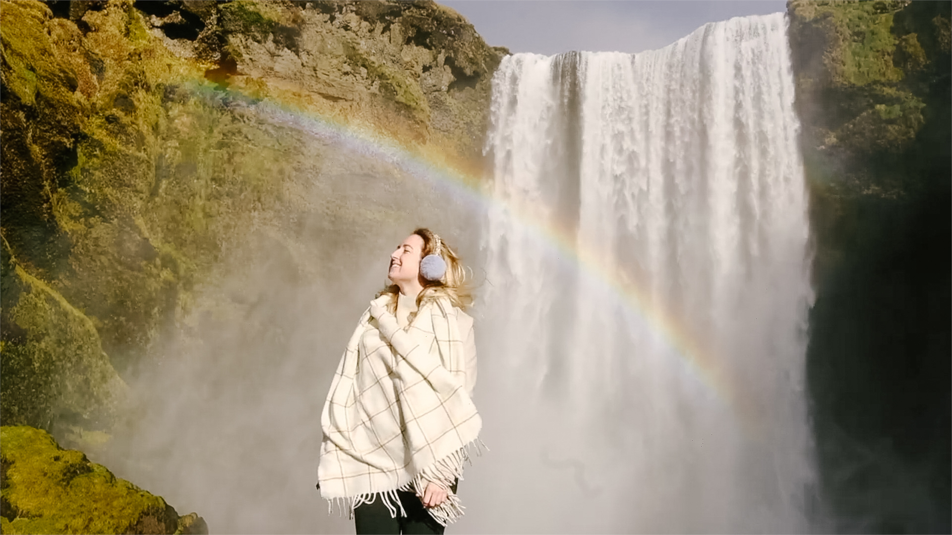 Helena Woods under rainbow in Iceland waterfall